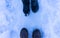 Two people, facing each other, on a snowy area. Only their feet are visible from a high vantage point