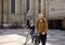 Two people - friends or couple, pushing their bicycles in a old city square in Europe, Serbia, Novi Sad. Smiling