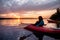 Two people in kayaks on the river on the scenic sunset