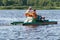 Two people in life jackets ride on an iron boat on the river, rear view