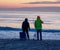 two people are looking out into the water on the beach