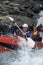 Two people paddling inflatable boat down rapids