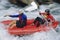 Two people paddling inflatable boat down rapids