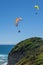 Two people paragliding above a rocky coast in New Zealand