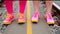 two people in pink and yellow shoes standing on train tracks