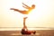 Two people practicing yoga in the sunset light on goa india beach. female and male acro yogi tantra flying copyspce