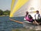 Two people sailing a small grey dinghy on a lake