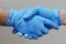 Two people shaking hands wearing surgical gloves