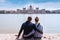 Two people sit on the waterfront and enjoy the view of the parliament in Budapest, Hungary