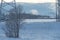 Two people skiing over the snowy field on cold winter evening