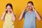 Two people standing in front of camera, female crying and looking disappointed, male keeps hands on temples and does not like her