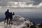 Two people standing on a snowy peak looking at the view