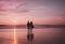 two people are walking on the beach holding surfboards at sunset