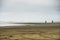 Two People Walking On The Sand Beach During Stormy Weather With The Rough Seas and Rolling Wave Beating The Shore