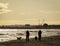 Two people walking their dogs along Roker beach on a bright sunny day, selective focus, landscape view.