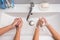 Two people wash their hands in the sink, top view