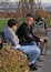 Two persons are talking at the bench in park of