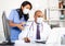 Two physicians in medical masks working with case histories on laptop