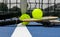 Two pickleball paddles and two yellow whiffle balls