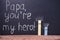 two pieces of chalk with eyes and handwritten text Papa youâ€™re my hero over black chalkboard, holiday concept of Fatherâ€™s Day