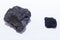 Two pieces of coal - large and small, lying next to a white background.