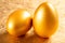 Two pieces gold eggs on golden background