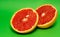 two pieces of grapefruit next to each other on green background