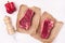 Two Pieces of Raw Fresh Beef Meat Steak on Craft Paper White Wooden Background Top View Pepper Mill and Ripe Red Pepper