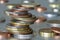 Two piles of shiny coins different sizes and colors stacked unevenly on each other on colorful blurred blue abstract background.