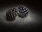 Two pine cones, touching, dark still life. Light painting.