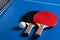 Two ping pong rackets. Table tennis rackets and a ball on a blue tennis table