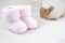 Two pink booties for babies with one toy sheep