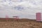 Two pink chairs, a table and a refrigerator stand in the Namib desert against the backdrop of a cloudy sky