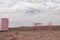 Two pink chairs, a table and a refrigerator stand in the Namib desert against the backdrop of a cloudy sky