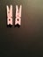 Two pink clothespins on a black background.