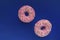 Two pink glazed donuts colorful sprinlkes floating