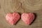 Two pink hearts made of woolen threads on a wooden background knitted in one knot