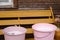 Two pink pail full fresh cow milk on wooden bench