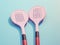 Two pink pickleball paddles against a blue background.