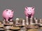 Two pink piggy banksstanding on a stock of gold coins