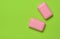 Two pink slices of soap on a green background. Minimalist trend, top view, copy space