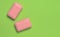 Two pink slices of soap on a green background. Minimalist trend, top view, copy space..