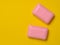 Two pink slices of soap on a yellow background. Minimalist trend, top view, copy space
