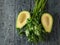 Two pitted avocado halves and parsley on a black wooden table. The view from the top