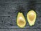 Two pitted avocado halves on a rustic table. The view from the top