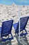 Two plastic chairs stand on beach under umbrella