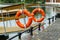 Two plastic orange lifebuoys hang at the entrance to the wooden pier.