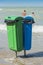 Two plastic trash recycling bins on the beach