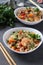 Two plates fried rice with seafood, vegetables, ginger and parsley on dark background. Asian cuisine. Vegetarian food. Vertical