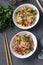 Two plates fried rice with seafood, vegetables, ginger and parsley on dark background. Asian cuisine. Vegetarian food. Vertical